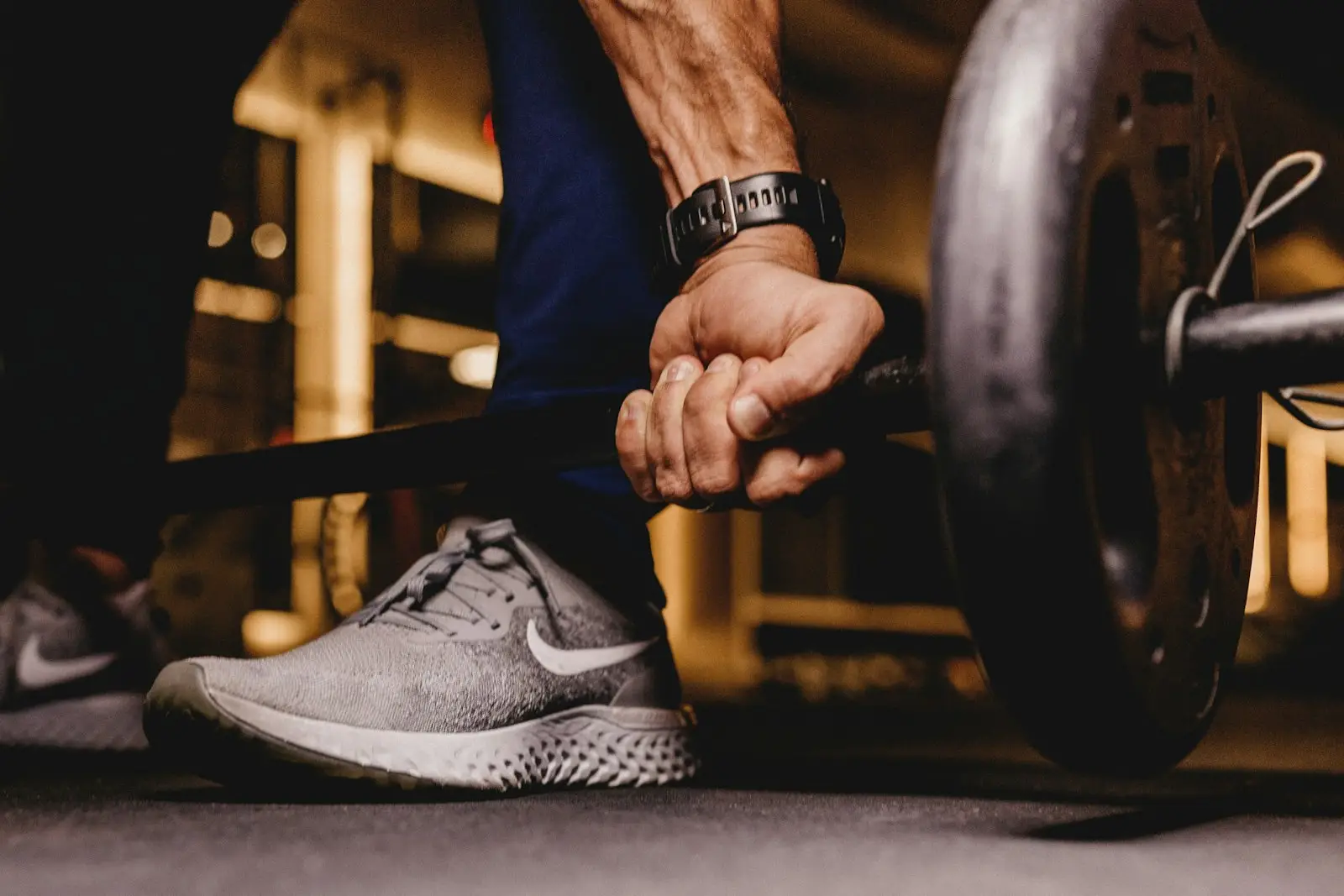 Hand gripping a barbell next to a weight plate