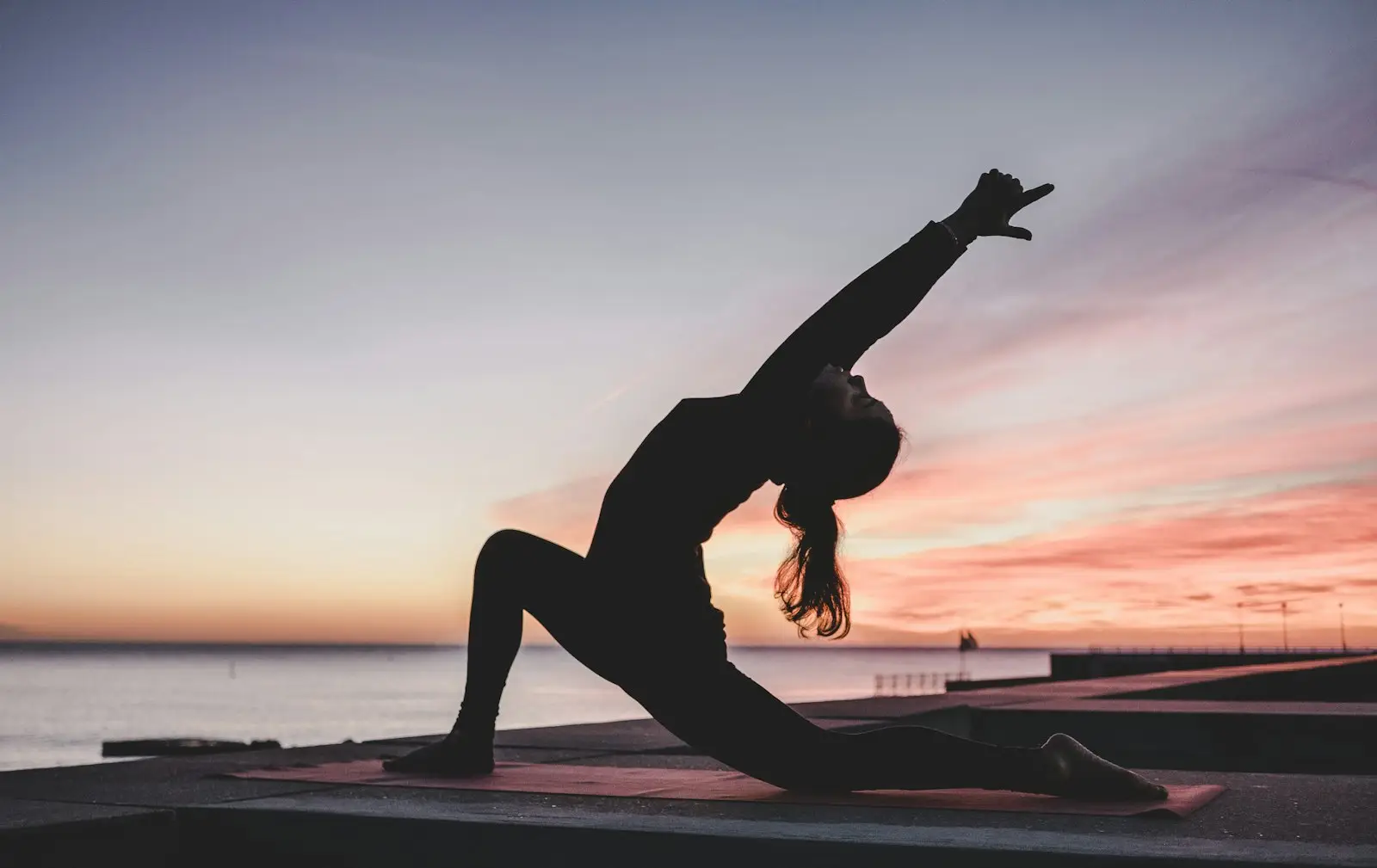 Yoga pose silhouetted against a sunset sky