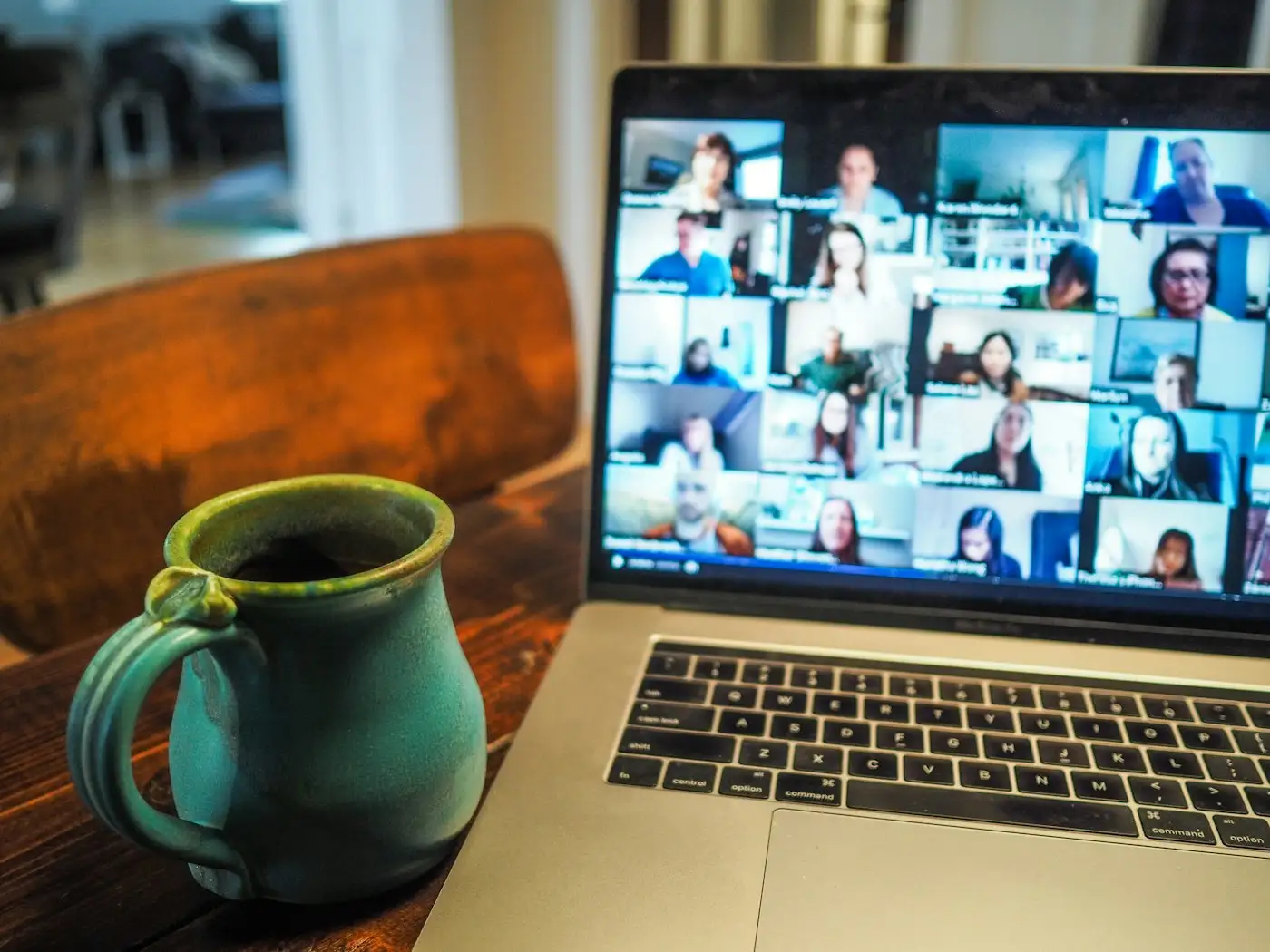 Laptop showing a group video call next to a mug